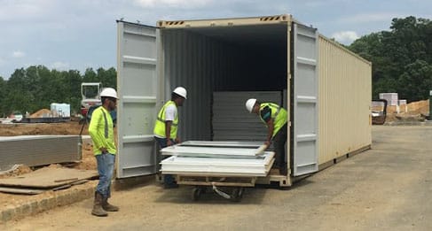 Image of a steel storage container for rent with construction workers removing materials